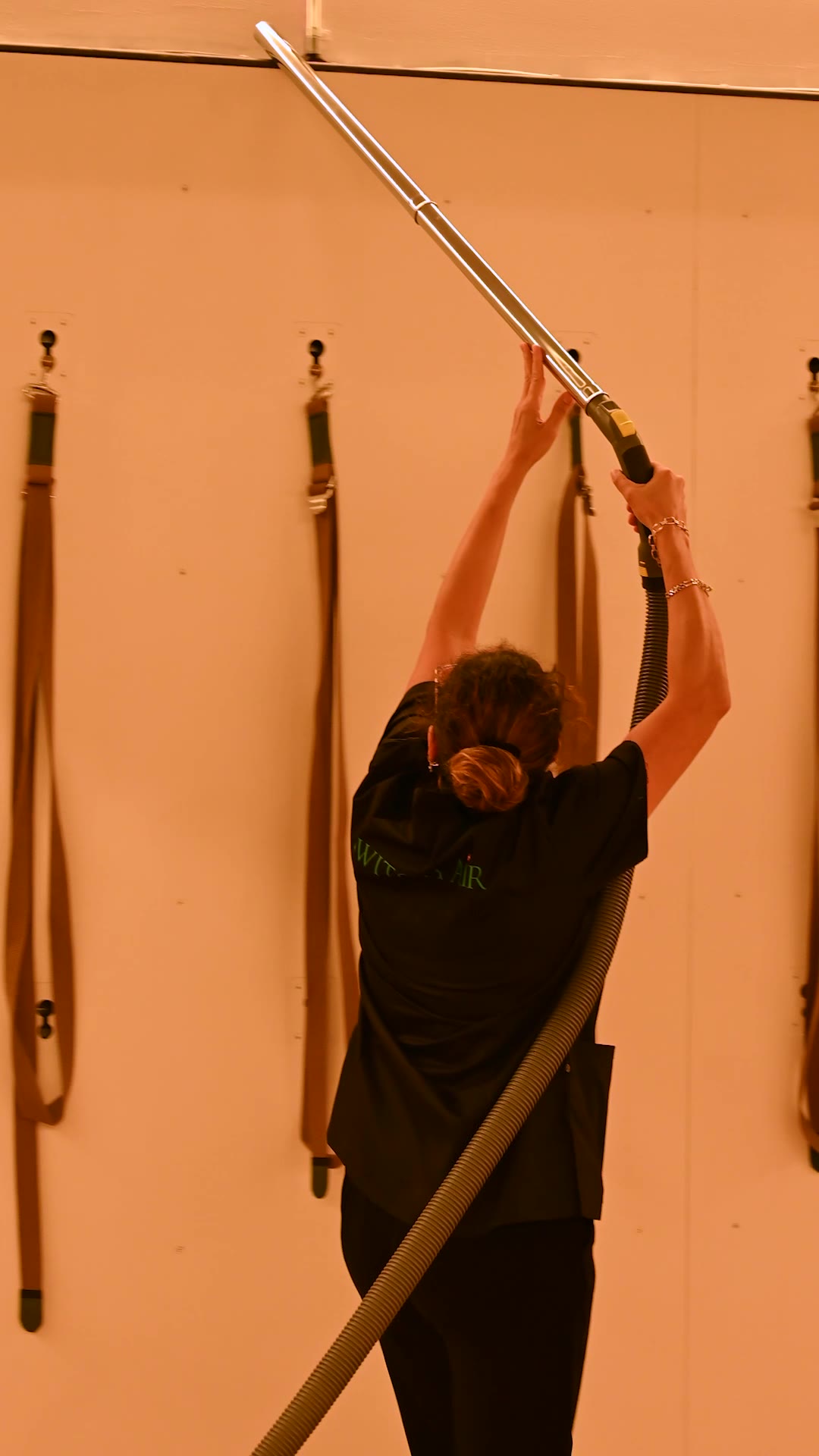 Dépoussiérage en hauteur des sangles murales d'un studio de Pilates