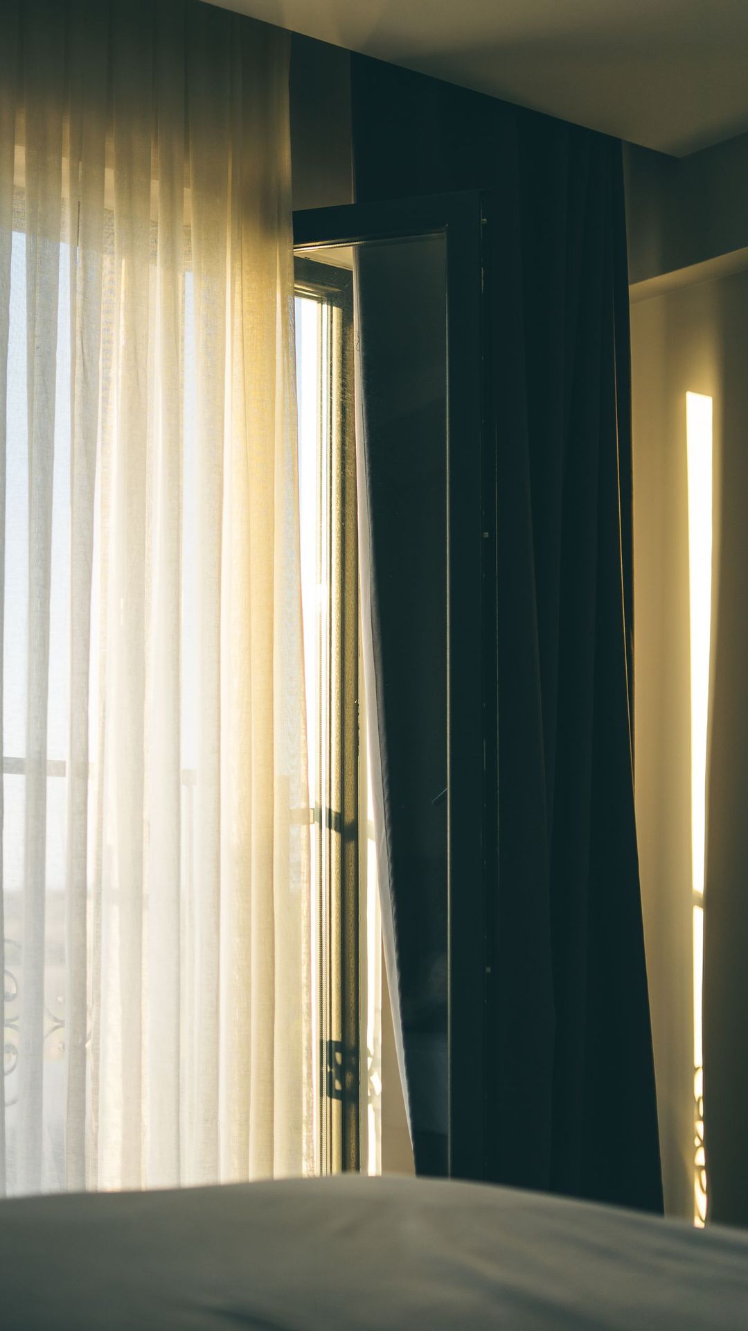 Chambre lumineuse avec rideaux clairs et fenêtre entrouverte, lumière du matin