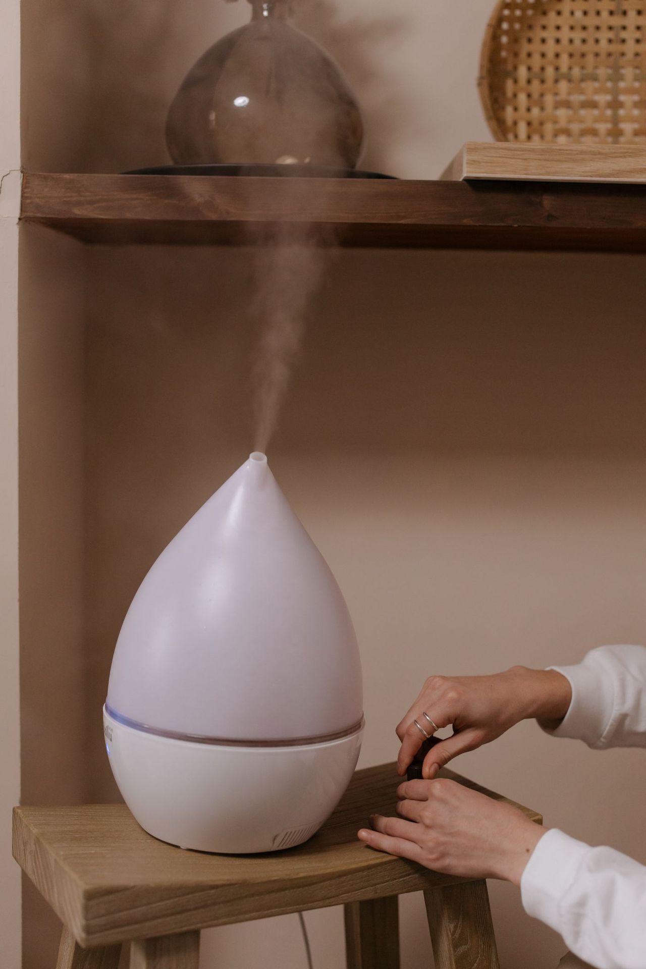 Diffuseur d'huiles essentielles qui diffuse une fine brume dans une étagère, lumière douce du soir
